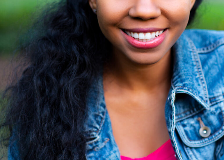 Sashani Nichole smiling in denim jacket and pink top, outdoor headshot
